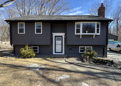Completed split-level home with new dark vinyl siding built by Lagace Construction