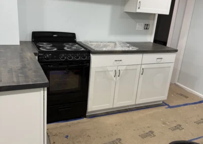 Newly remodeled kitchen with black stove, white cabinets, and a countertop. Floor covered with protective paper, indicating ongoing renovation